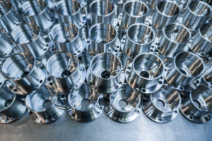 a batch of shiny aluminium aerospace parts made with cnc machine - close-up with background blur, industrial backdrop